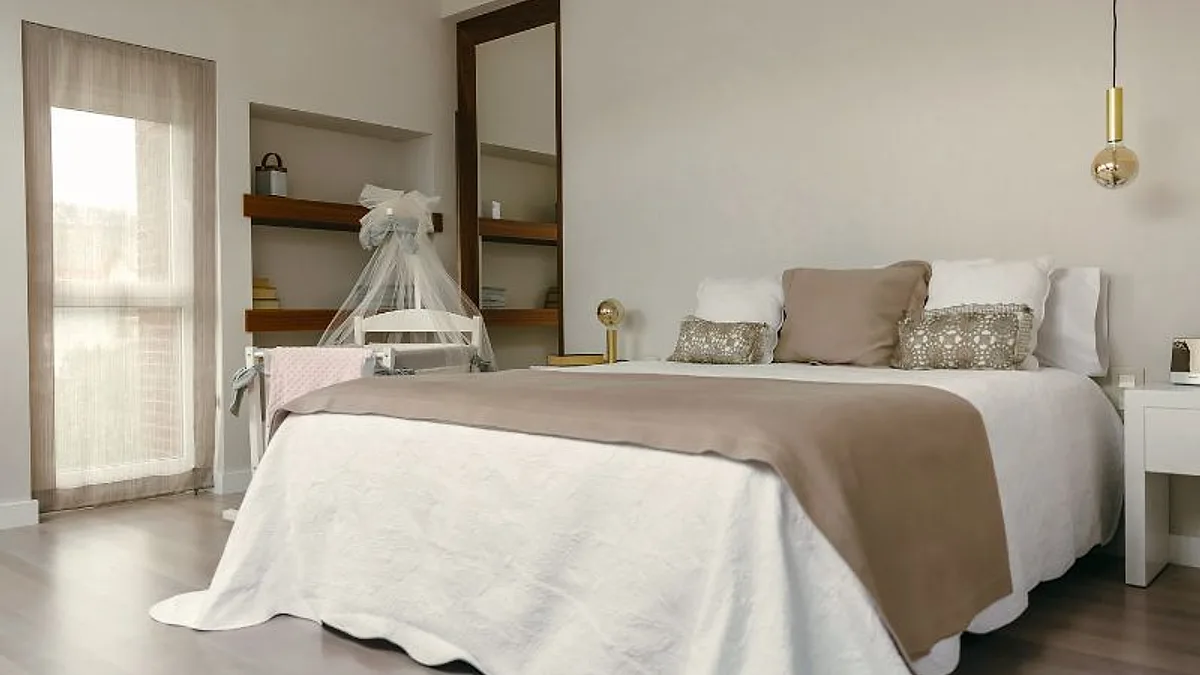 Quarto claro com cama de casal arrumada com colcha bege