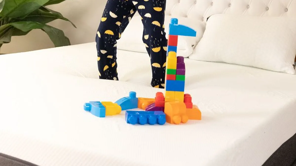 Pés de criança sobre a cama ao lado de blocos de montar coloridos