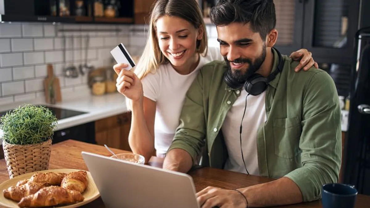 Casal sorrindo em frente ao notebook enquanto faz uma compra online