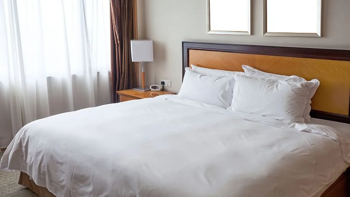 Quarto de hotel com cama de casal arrumada com roupa de cama branca